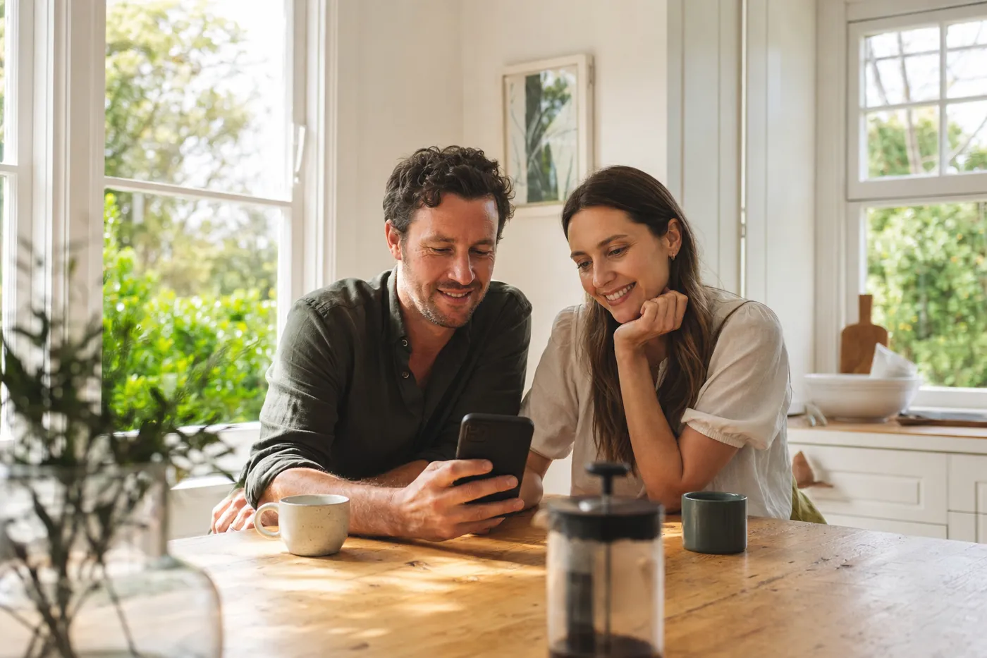 A couple at a kitchen table looking at a phone together